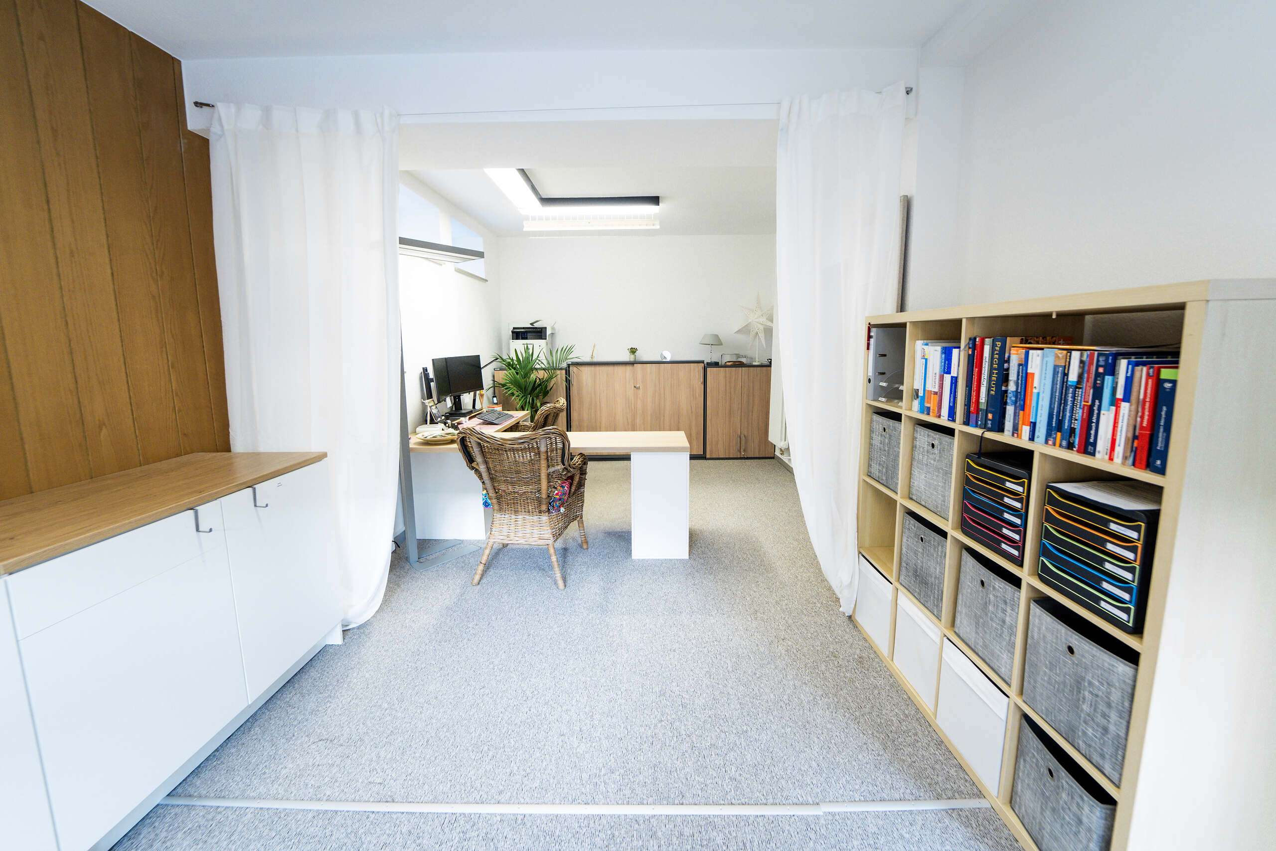 Ein Büro mit einem Schreibtisch, einem Stuhl und Regalen voller Bücher und Ordner.